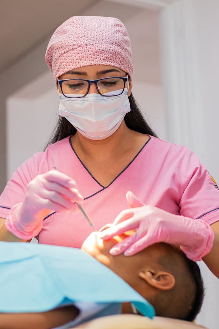 A dentist in pink uniform examining a patient's teeth, focusing on dental care.